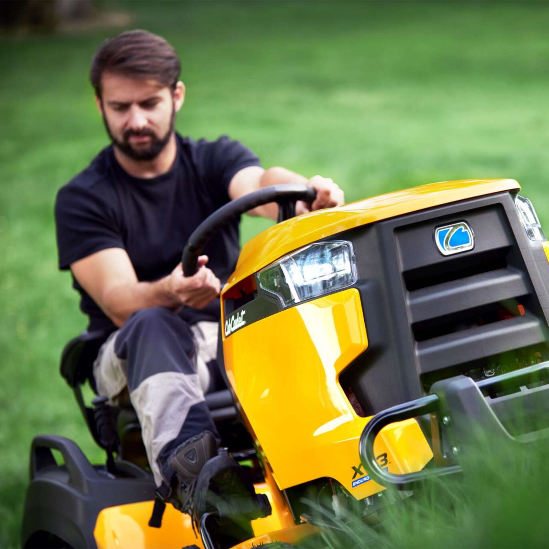 Mann fährt einen Cub Cadet Rasentraktor über eine grüne Rasenfläche – Einsatz in Bewegung.