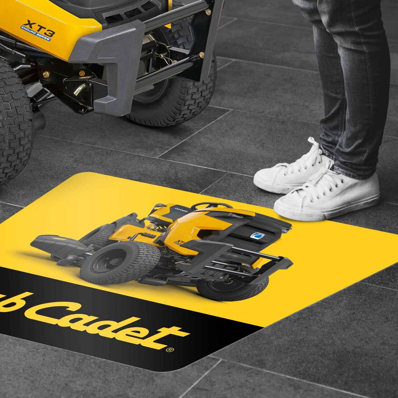 Cub Cadet Bodenmatte mit Produktabbildung und Logo – Person steht davor im Verkaufsraum.