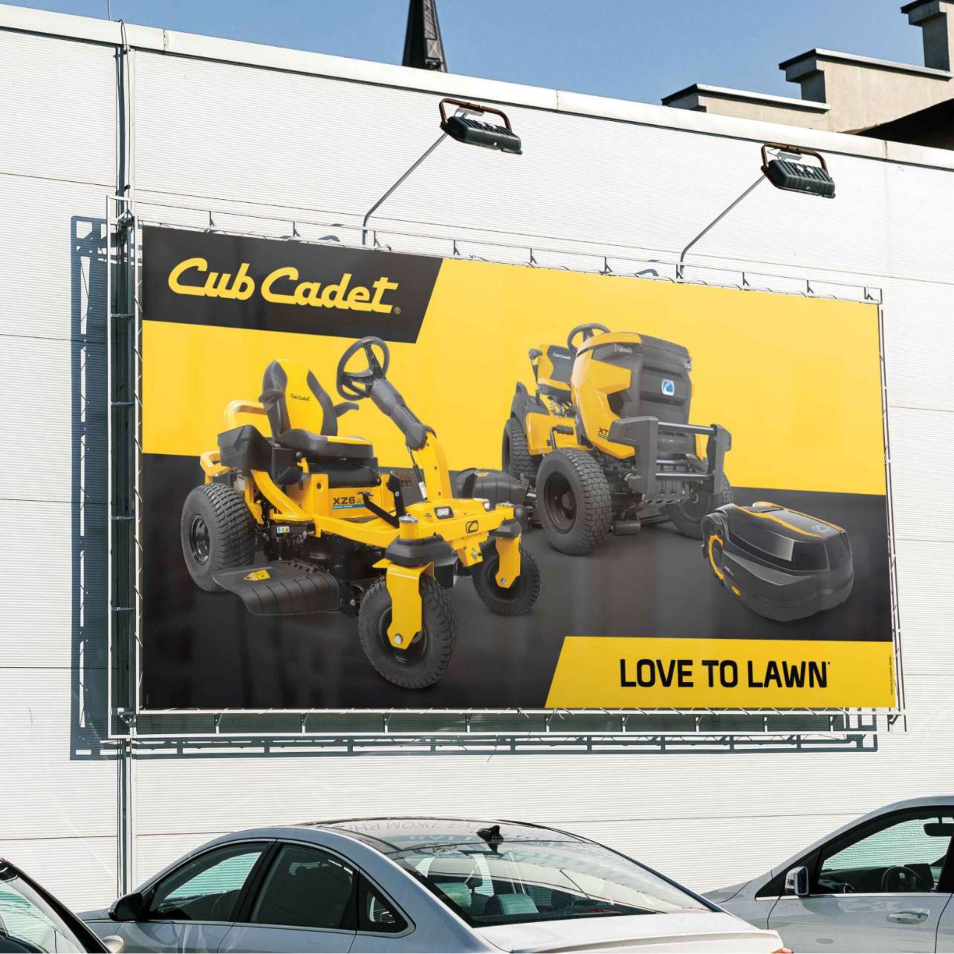 Outdoor-Werbeplakat von Cub Cadet an einer Gebäudefassade – Aufsitz- und Zero-Turn-Mäher im Fokus.